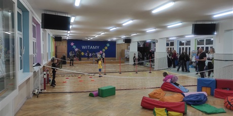 Powiększ grafikę: Uczestnicy Dnia Otwartego Szkoły Podstawowej nr 48 w Gdańsku. Korytarz szkolny. Wiele osób uczestniczy w różnych grach i zabawach.