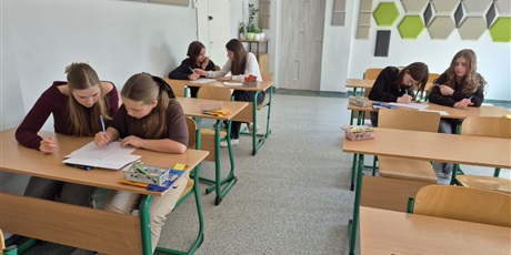 Powiększ grafikę: Uczniowie podczas konkursu. Siedzą w ławkach.